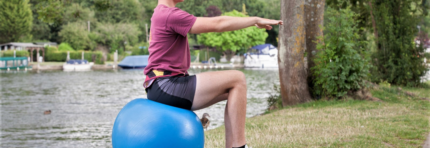 young man doing Pilates exercise on Swiss ball