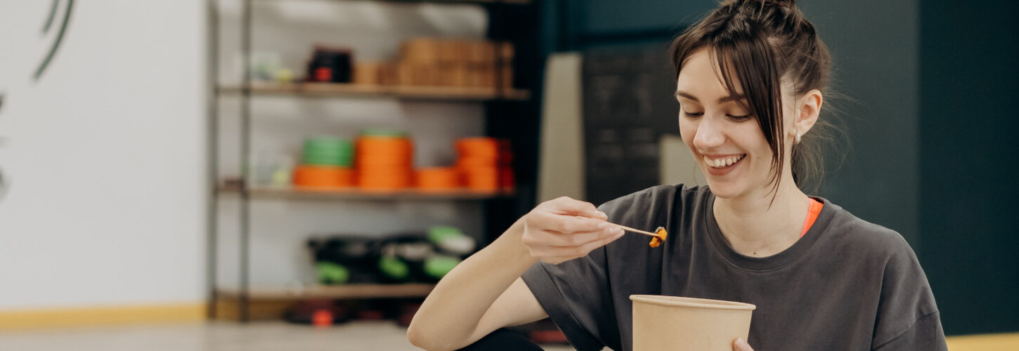 Woman eating out of cardboard tub