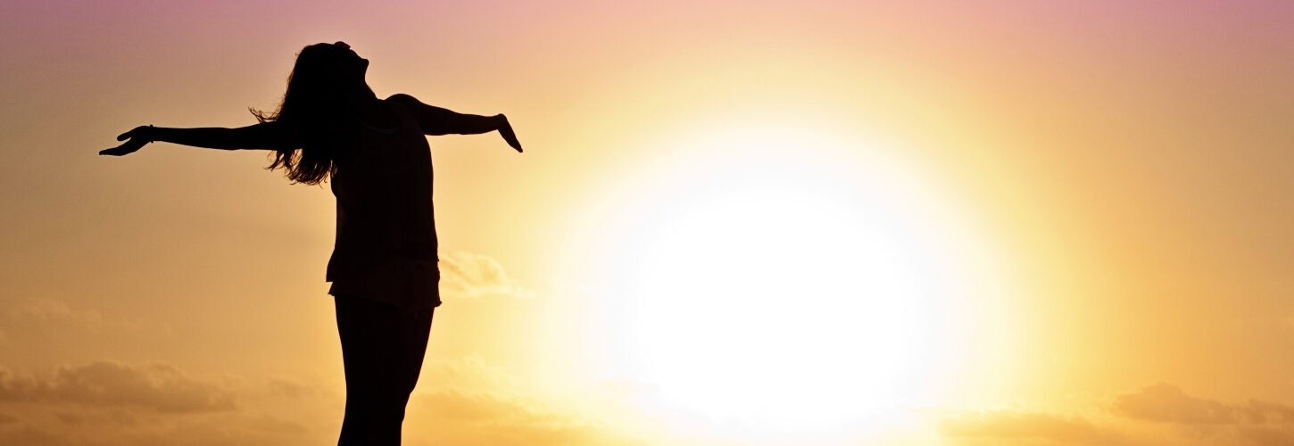 Woman with arms outstretched at sunrise
