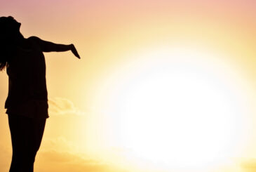 Woman with arms outstretched at sunrise