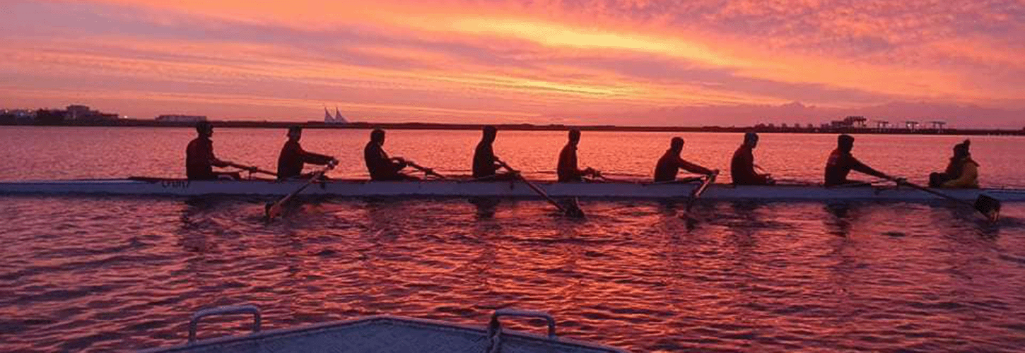 Student rowing eight at sunset