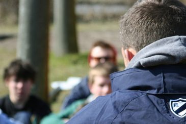 coach with young rowers at boathouse