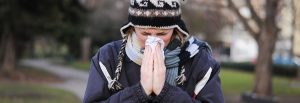 woman sneezing into tissue