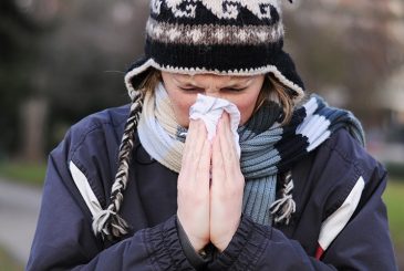 woman sneezing into tissue