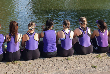 9 rowers in purple kit watching the river