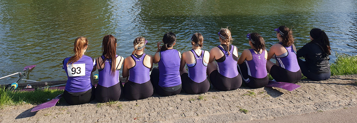 9 rowers in purple kit watching the river