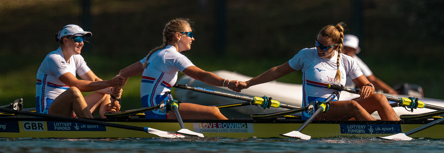 women in a crew joining hands after a race