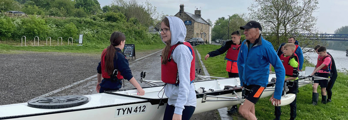 Coaches and young people carrying Tyne ARC boat