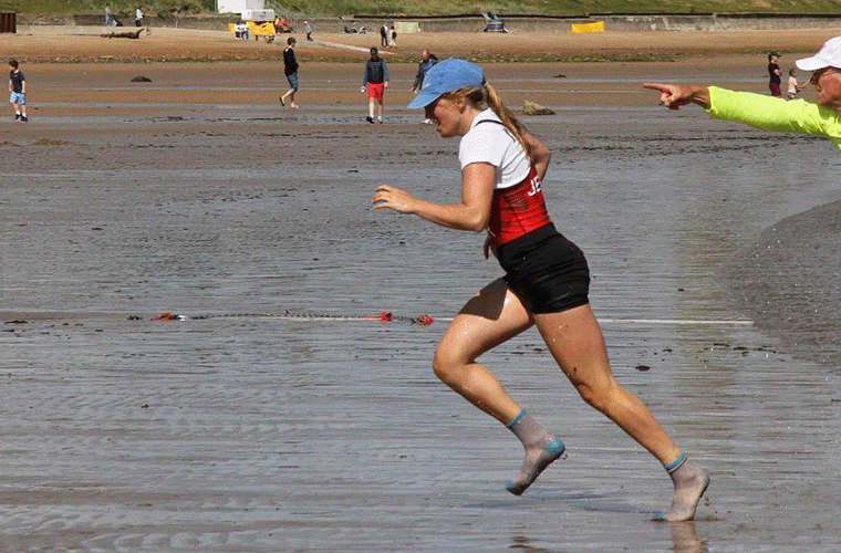 coastal sculler sprinting up beach