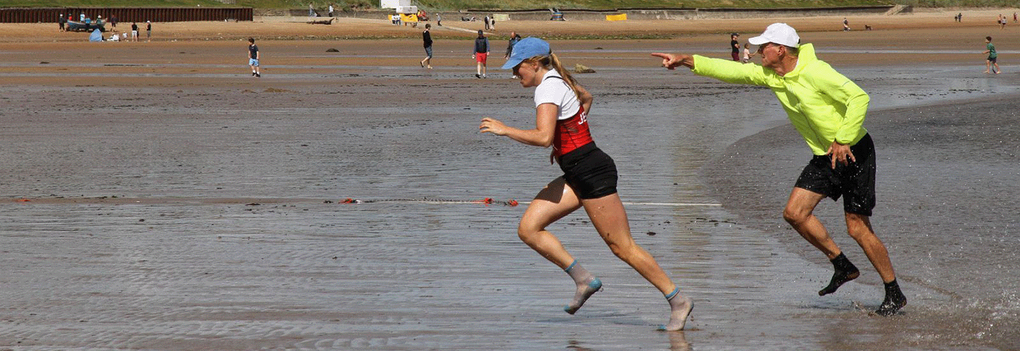 coastal sculler sprinting up beach